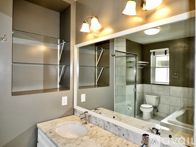 A bathroom with a marble countertop and a walk-in shower.