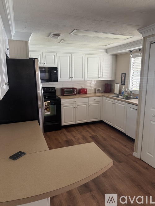 A kitchen with black appliances and white cabinets.