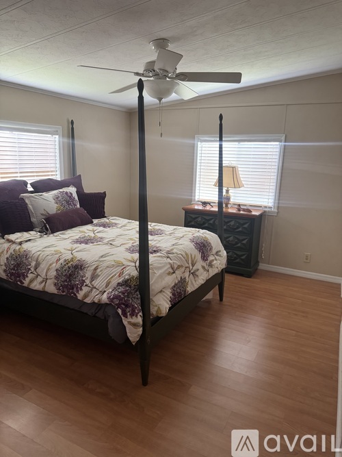A bedroom with a four poster bed and a ceiling fan.