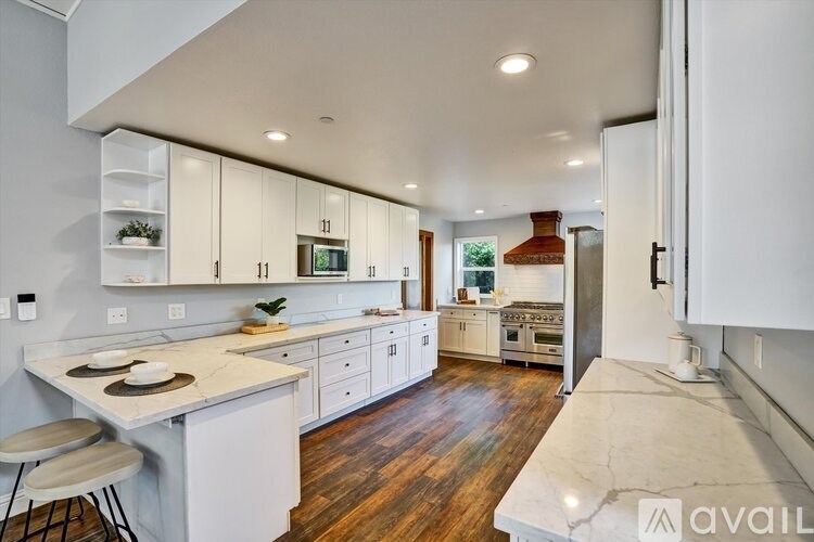A modern kitchen with white cabinets and a wooden floor.