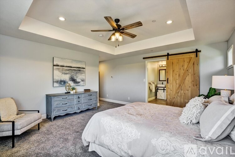 A bedroom with a large bed, a ceiling fan, and a painting on the wall.