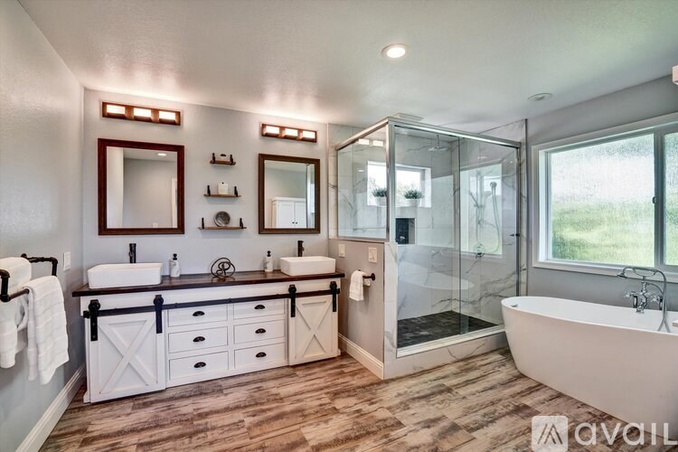 A bathroom with a white tub, double sinks and a walk in shower.