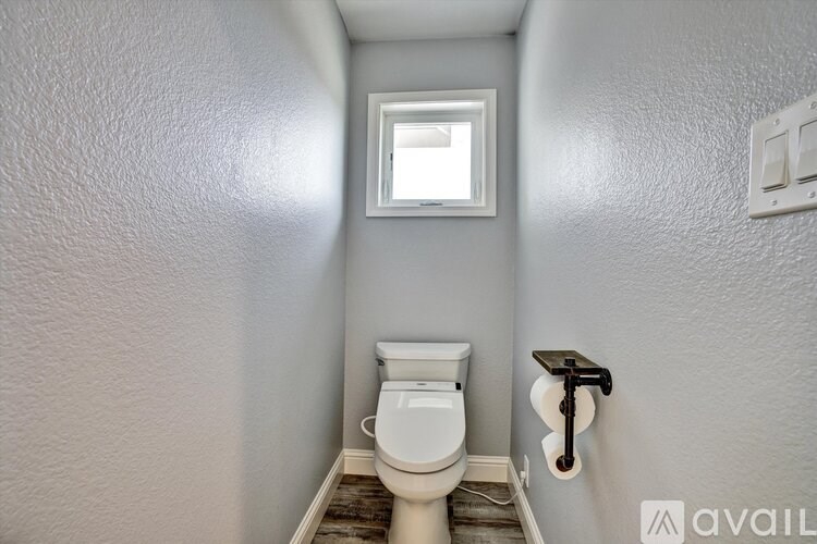 A small bathroom with a toilet and a window.