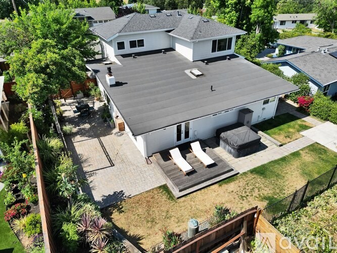 A large white house with a grey roof and a patio with a table and chairs.