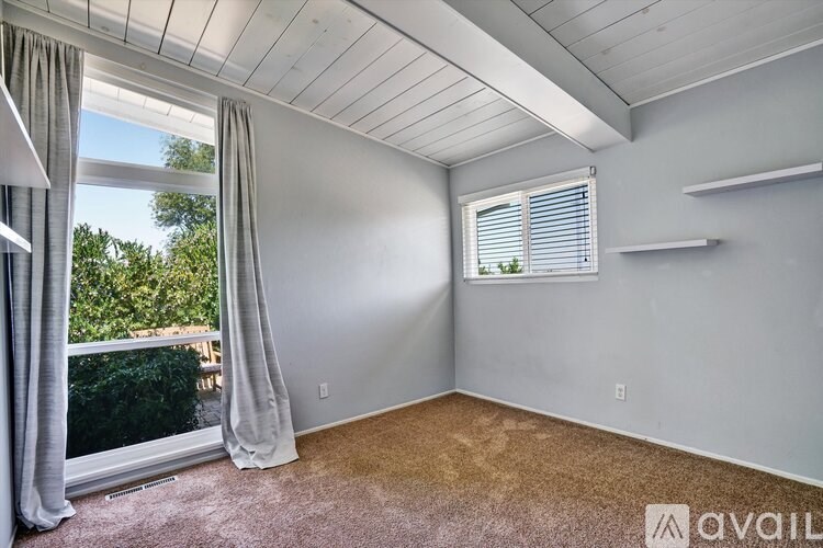 A room with a window and a balcony overlooking trees.