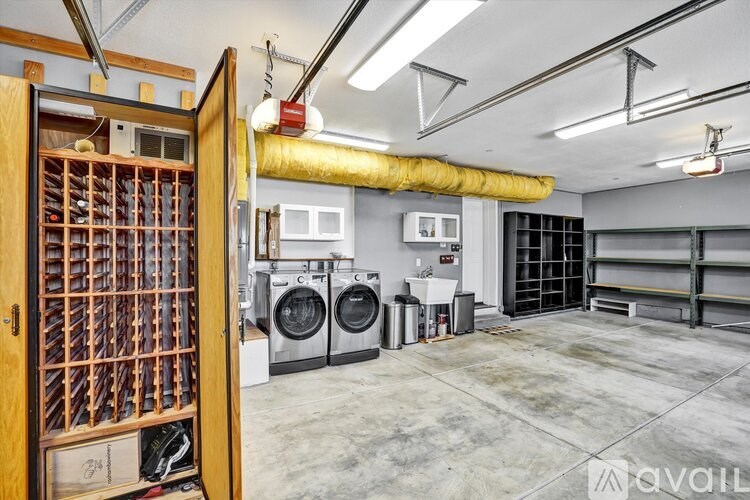 A laundry room with a washer and dryer, a shelf, and a door open to a storage area.