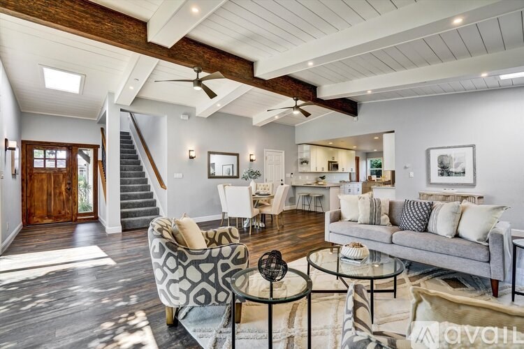 A living room with a grey couch and a glass table.