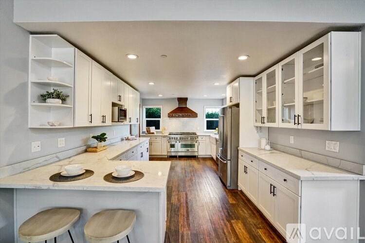 A modern kitchen with white cabinets and a wooden floor.