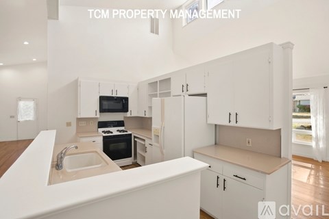 A modern kitchen with white cabinets and appliances, with the text "TCM PROPERTY MANAGEMENT" and "available" overlaid on the image.