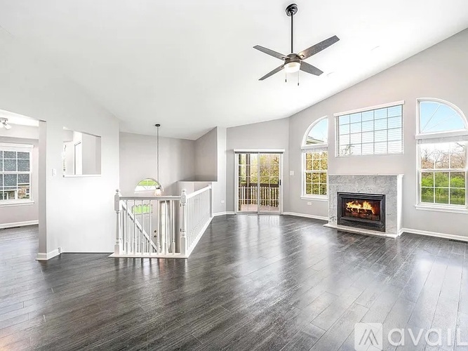 A spacious living room with a fireplace and a ceiling fan.