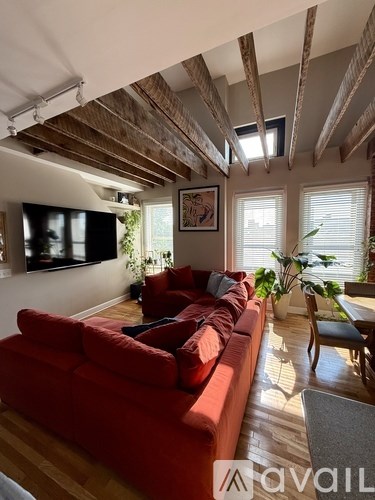 A living room with a red couch and wooden beams on the ceiling.