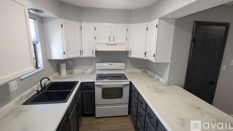 A kitchen with white cabinets and a marble countertop.