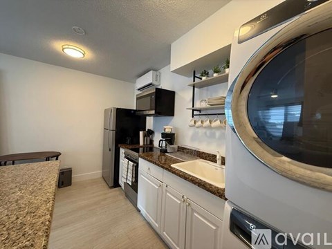 A kitchen with white cabinets and a black refrigerator.