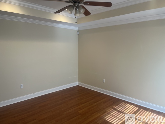A room with a ceiling fan and wooden flooring.