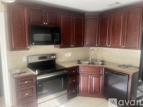 A kitchen with brown cabinets and a black microwave.
