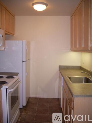 A kitchen with a white refrigerator, stove, and sink.