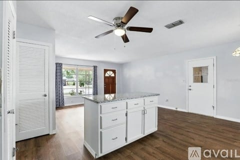 A kitchen with white cabinets and a ceiling fan.
