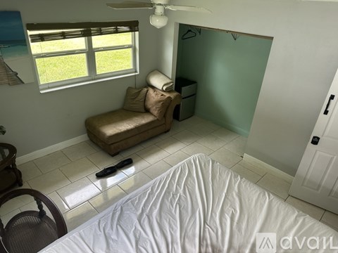 A bedroom with a bed, chair, and window.