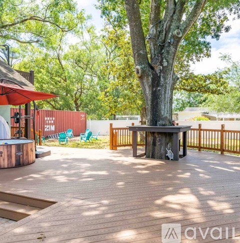 A wooden deck with a table and chairs and a tree in the middle.