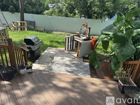 A backyard with a wooden deck and a trash can.