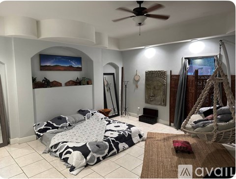 A living room with a hanging swing chair and a large bed with a black and white pattern.