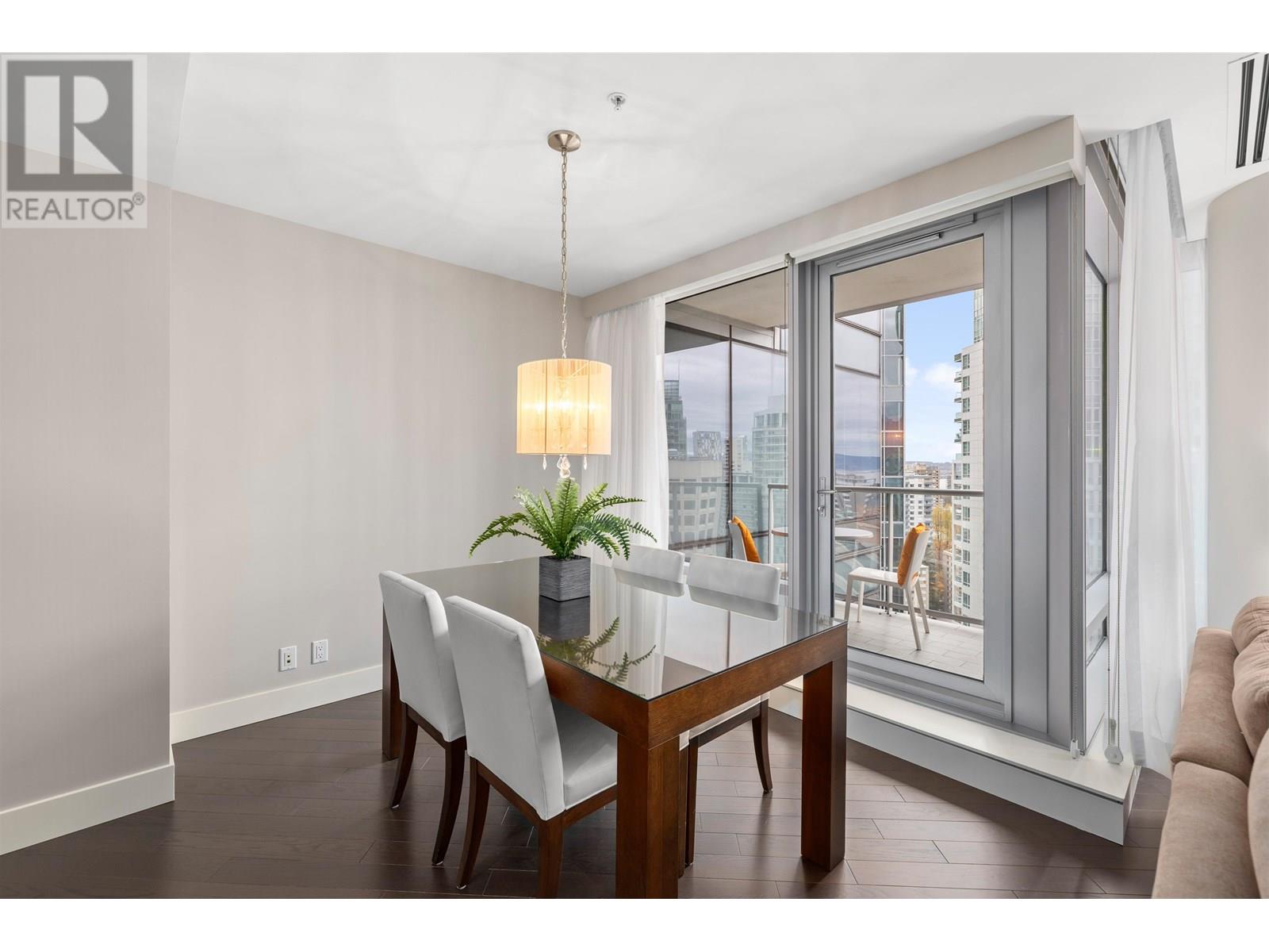 A dining room with a table and chairs and a window with a view of the city.