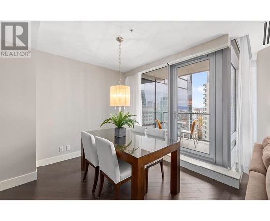 A dining room with a table and chairs and a window with a view of the city.