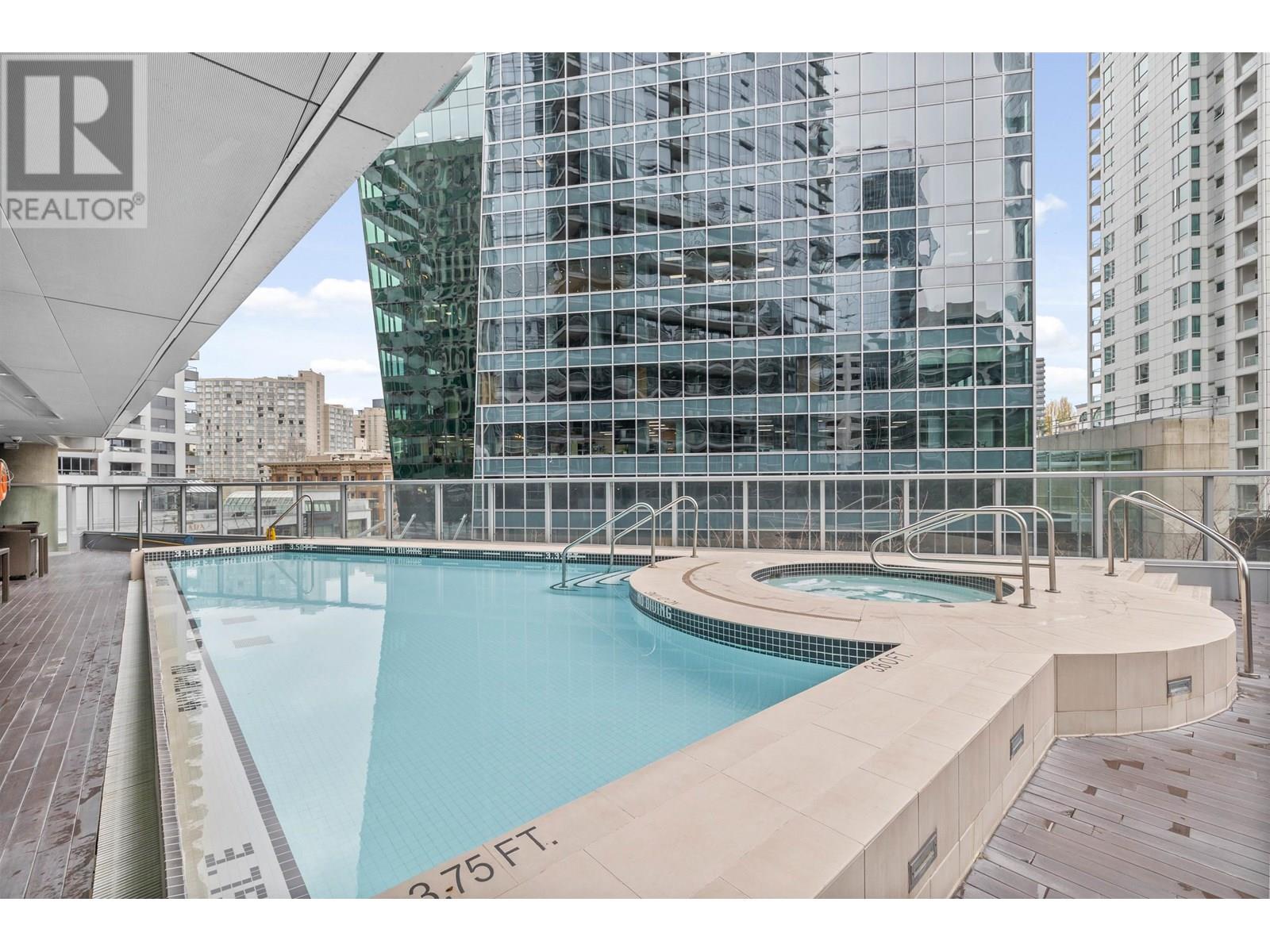 A swimming pool on a rooftop with a glass wall behind it.