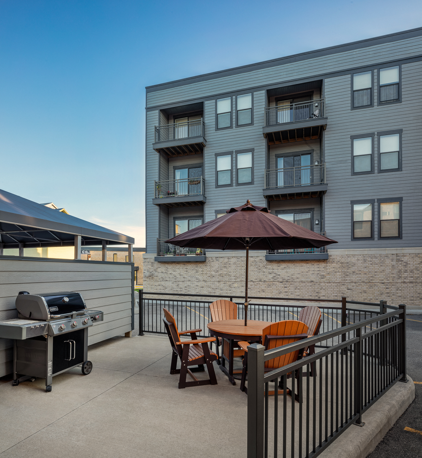 a patio with an umbrella and a table with chairs and a grill