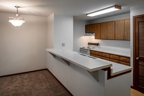 a kitchen with a white counter top and a stove and wooden cabinets