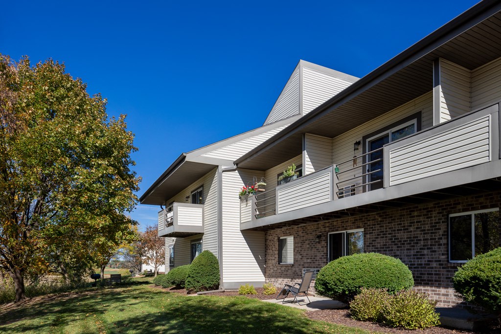 an apartment building with a lawn and trees in front of it