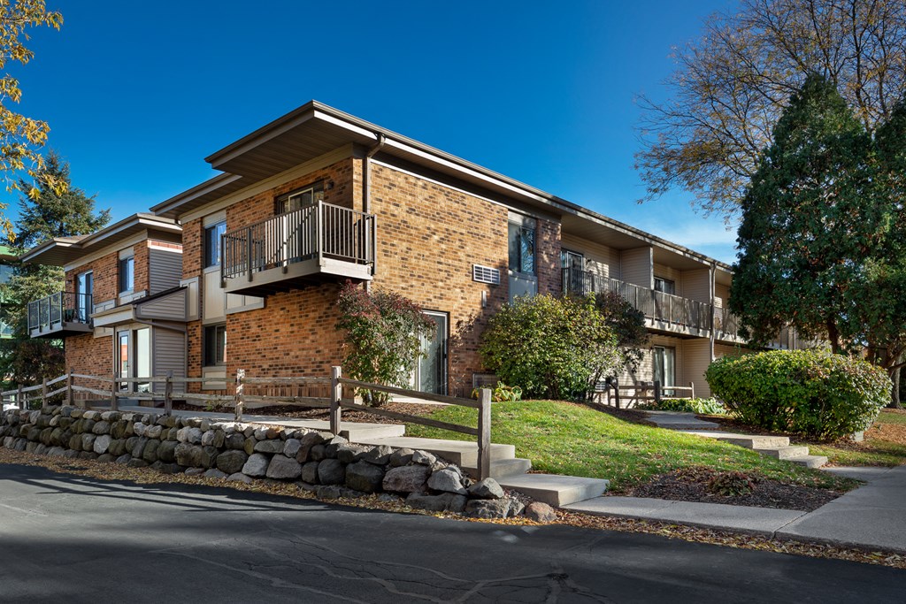 a brick apartment building with stairs and a stone retaining wall