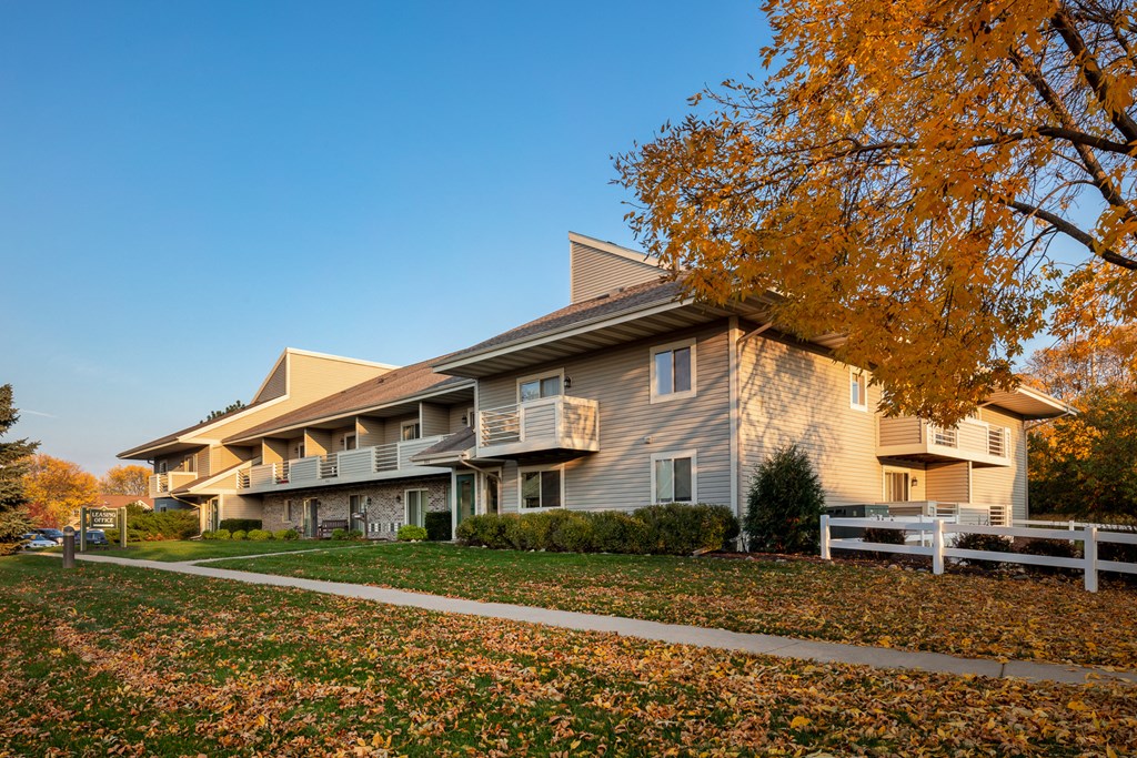 an apartment building in the fall with leaves on the ground
