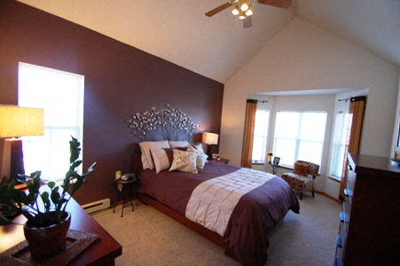 a bedroom with a large bed and a brown accent wall
