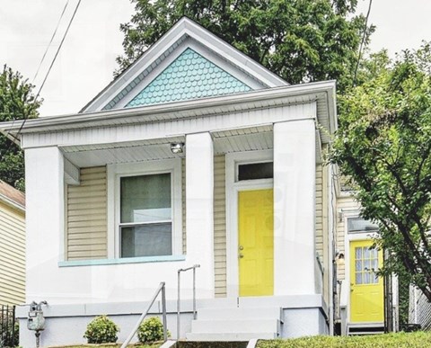A small white house with a yellow door and a blue window.