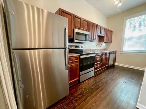 A kitchen with a stainless steel refrigerator and wooden cabinets.