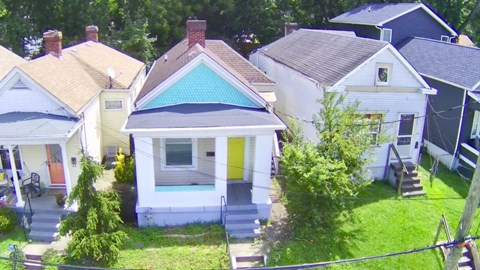 A small house with a blue roof is in the middle of a cluster of houses.