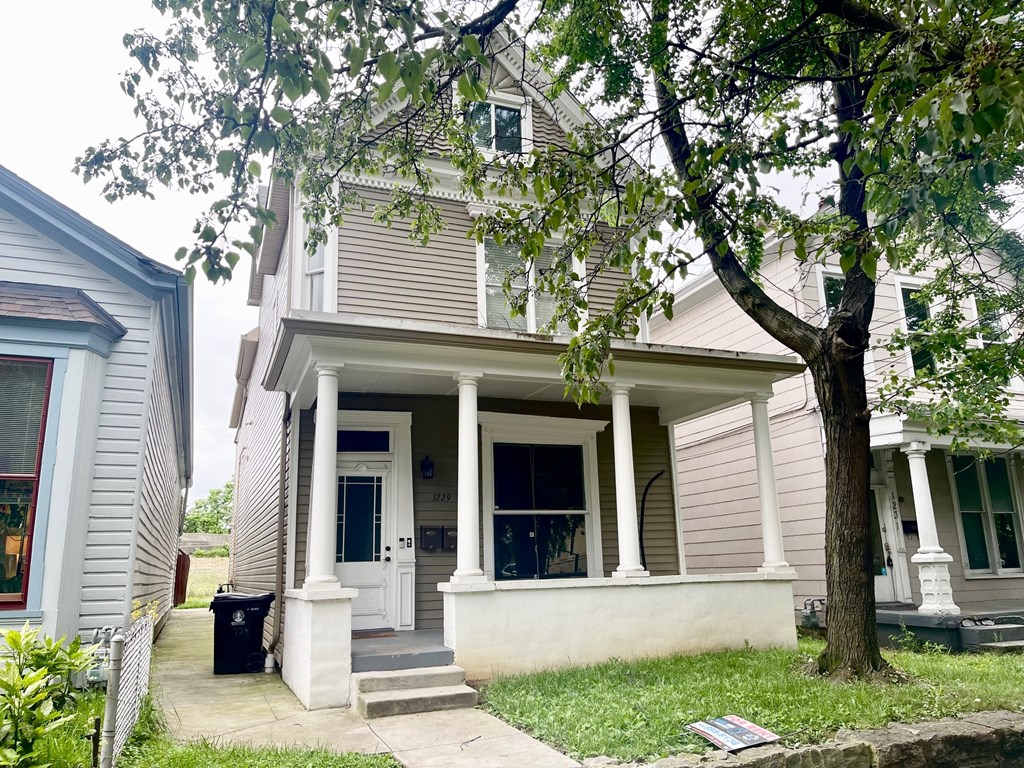 A house with a front porch and a tree in front.