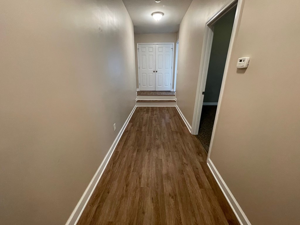 A hallway with wood flooring and white walls.
