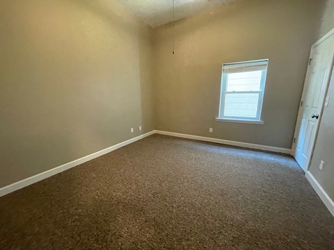 A room with a carpeted floor and a window.