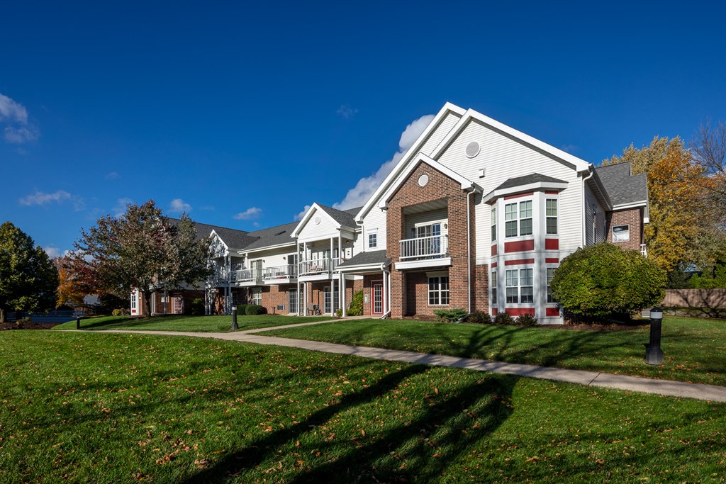 a row of houses on a green lawn with a sidewalk