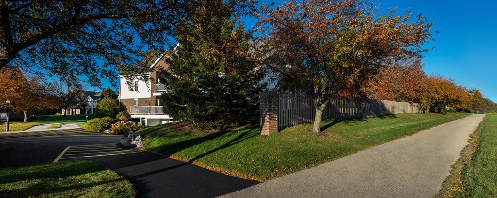 a sidewalk in front of a house with trees