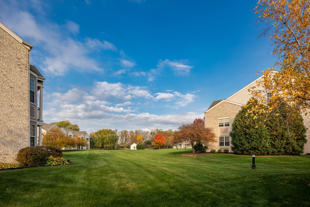 a green lawn in front of a building with trees