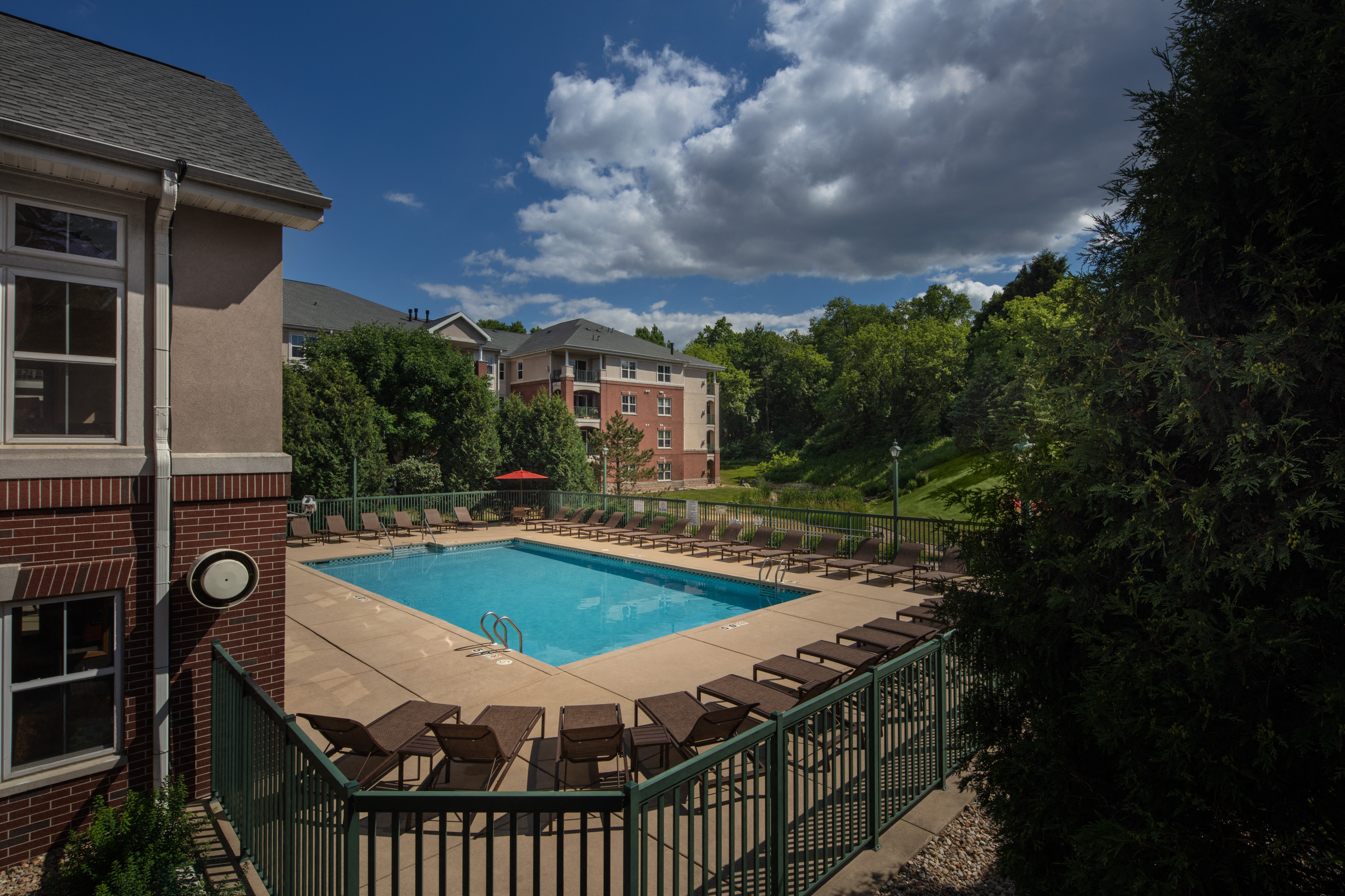 a swimming pool with chairs around it in front of a building