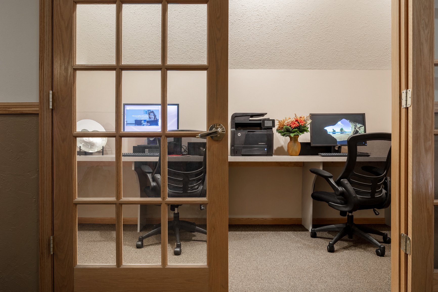 an office with a desk with two computers and a chair