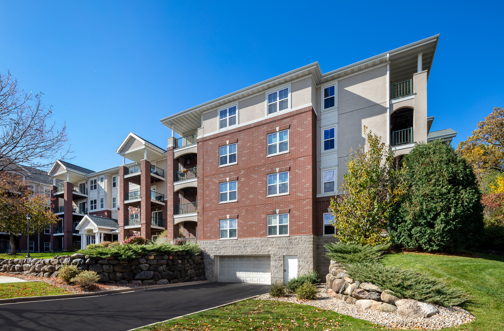 an apartment building with a stone wall and landscaping