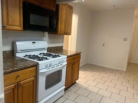 A kitchen with a white stove and wooden cabinets.