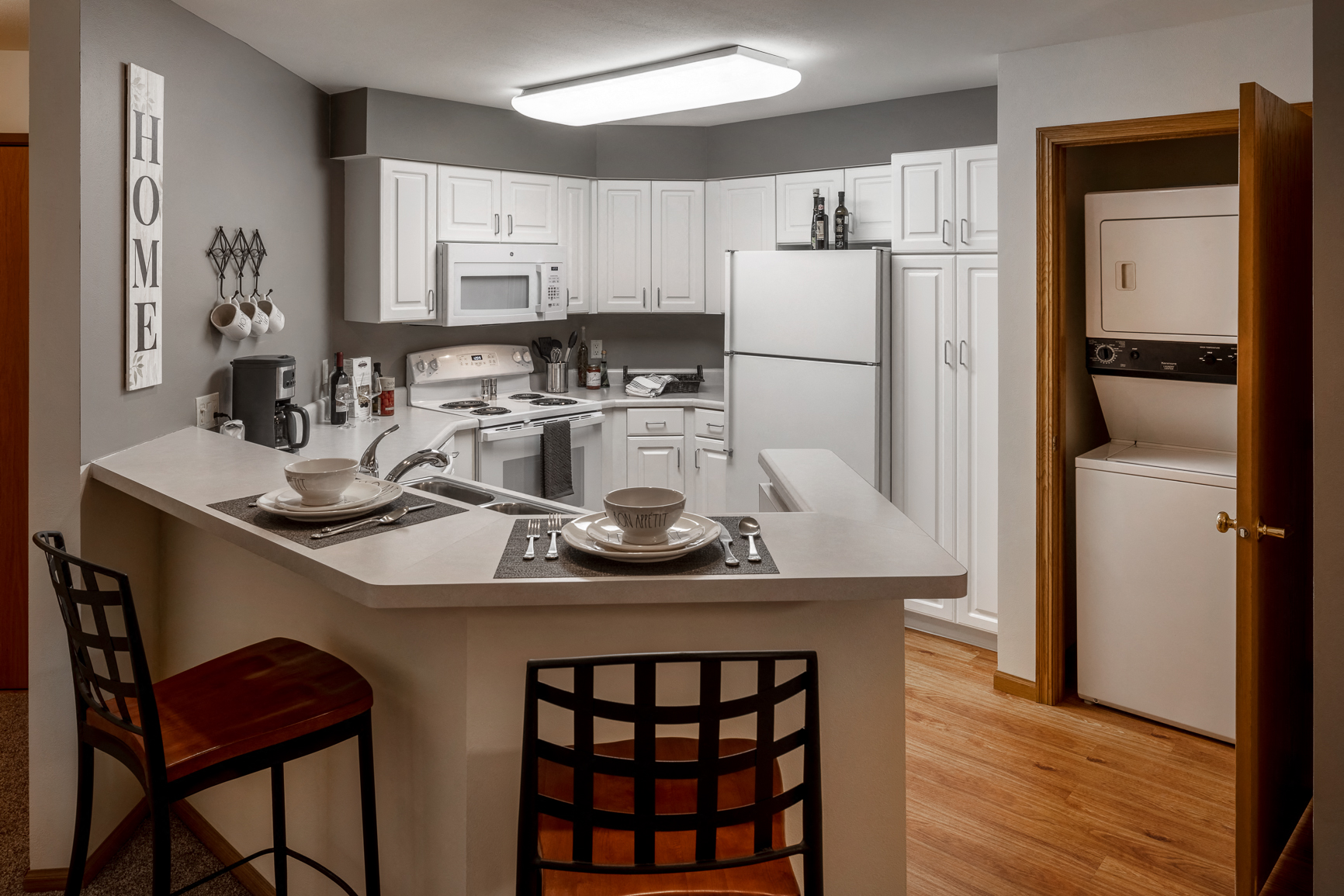 a kitchen with a center island with two chairs and a white refrigerator