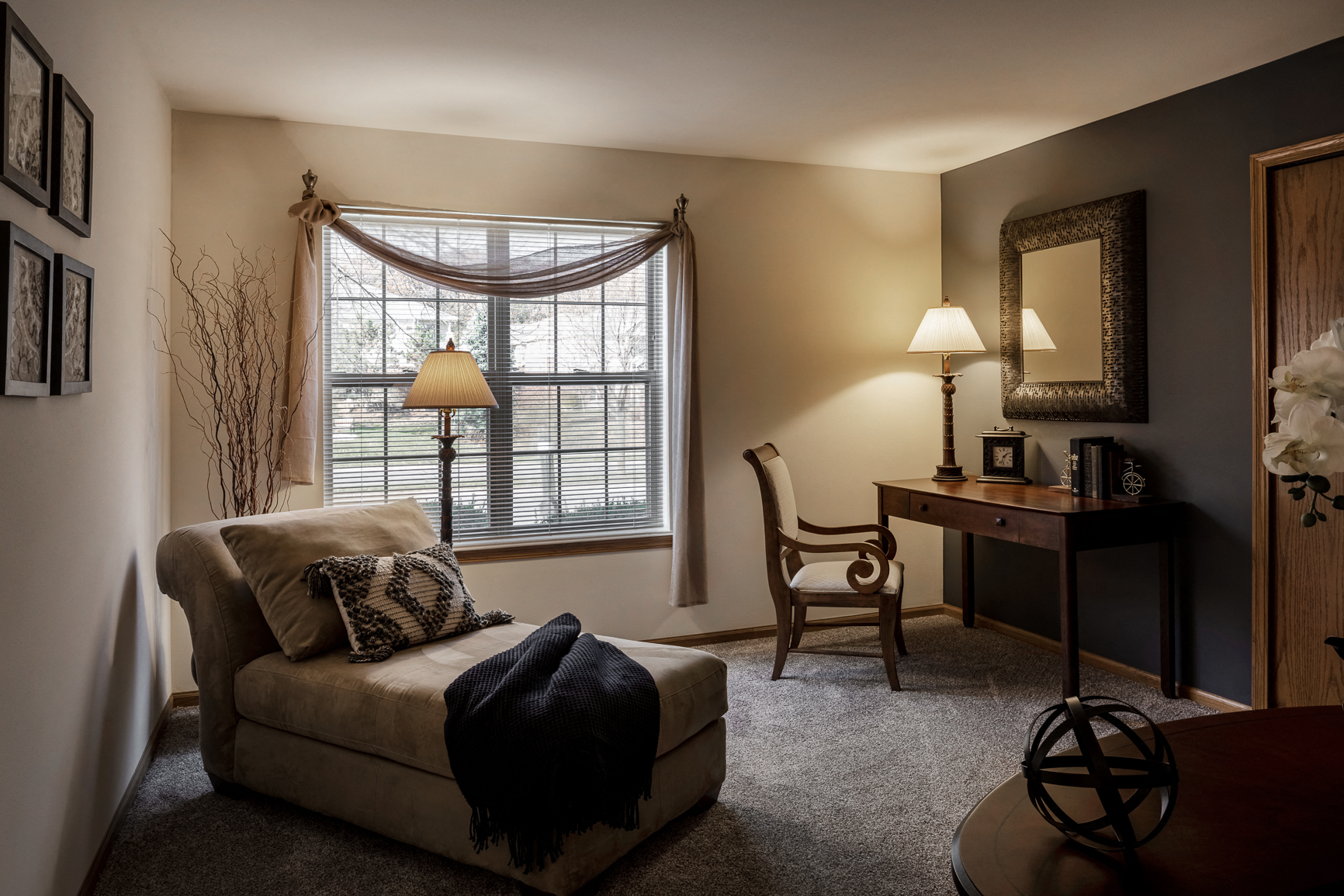 a living room with a couch and a desk and a window