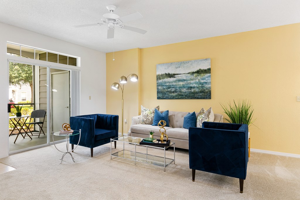 a living room with a couch and chairs and a ceiling fan
